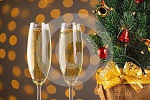 Two wine glasses with bubbly Champagne on blurry sparkling lights background and Christmas tree