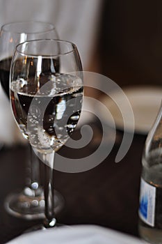 Two wine glasses filled with red wine, sparkling water or other drinks on a wooden table in a restaurant. Elegant dinner
