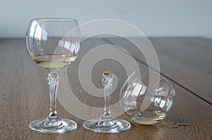 Two wine glasses. One half full broken glass and another half full undamaged wine glass on wooden table photo