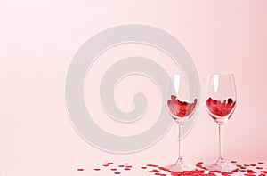 Two wine glasses with red hearts on pink background. Valentines day concept