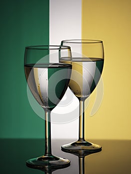 Two wine glasses silhouette full on irish flag background. Alcohol beverage