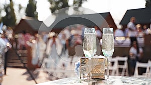 Two wine glasses with sparkling champagne on wedding ceremony table next to rings.