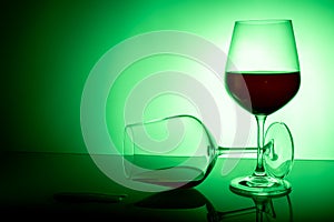 Two wine glasses on a white background, one glass half full the second lies, spilled wine