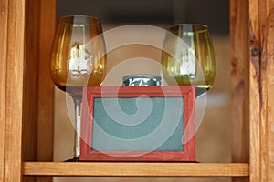 Two wine glasses on wooden shelf with frame