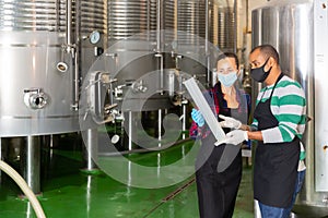 Two winemakers checking winemaking process at factory