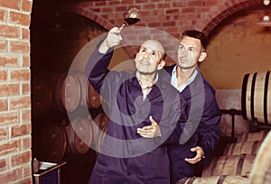 Two winemakers with sample of wine in cellar