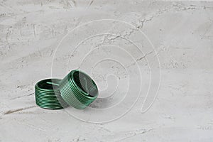 Two wire green thread inserts, free running on grey cement background. Stainless Steel. Horizontal with copy space for text and