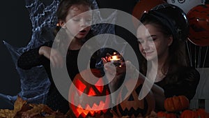 Two witches cast spells in the dark on Halloween on a black background with spider webs, autumn leaves and balloons
