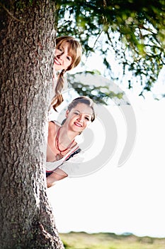 Two Woman behind a Tree