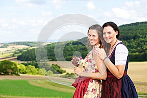 Two woman in dirndl standing in meadow