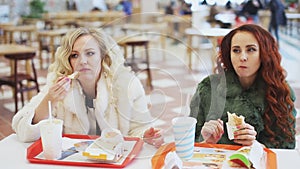 Two woman eating junk food in fast food restaurant