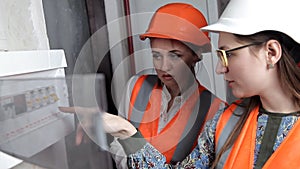 Two woman engineers checking technical data of heating system equipment in a boiler room