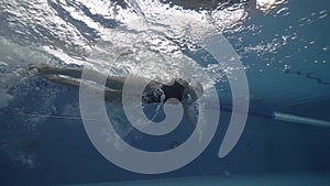 Two woman friends in chiffon dress swimming together underwater on dark background