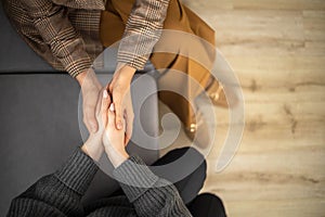 Two woman holding hands to each other concept of support care trust help sisterhood top view closeup