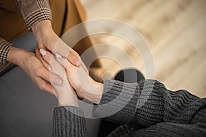 Two woman holding hands to each other concept of support care trust help sisterhood top view closeup