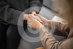 Two woman holding hands to each other concept of support care trust help sisterhood top view closeup