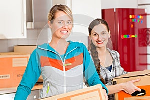 Two woman with moving box in her house