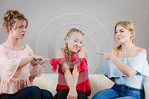 Two woman pointing at her female friend