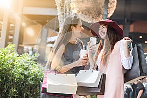 Two woman shopping together with shopping bags in hand and using