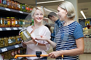 Two women of all ages are buying pickles at supermarket