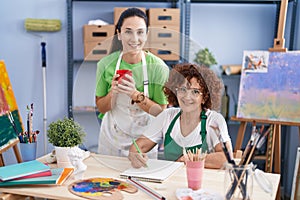 Two women artists drawing on notebook drinking coffee at art studio