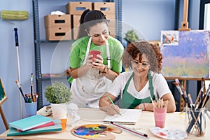 Two women artists drawing on notebook drinking coffee at art studio