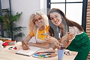 Two women artists drinking coffee drawing at art studio