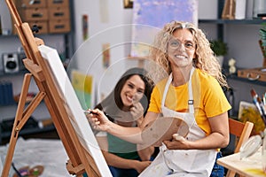 Two women artists smiling confident drawing at art studio