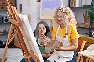 Two women artists smiling confident drawing at art studio