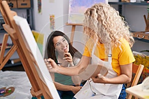 Two women artists smiling confident drawing at art studio