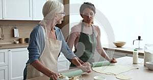 Two women blab while flattening dough in the kitchen