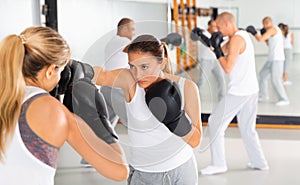 Two women in boxing gloves have boxing fight in the gym