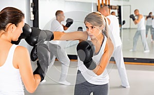 Two women in boxing gloves have boxing fight in the gym