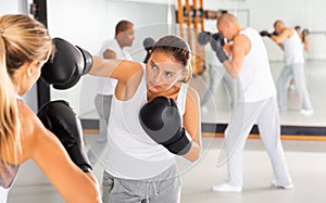 Two women in boxing gloves have boxing fight in the gym