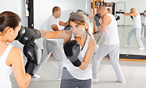 Two women in boxing gloves have boxing fight in the gym