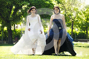 Two women brides with wedding dress back and white walking in a park