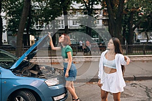 Two women with broken car road look for help.