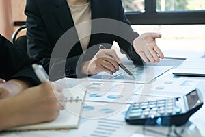 Two women in business suits are discussing a report on a table