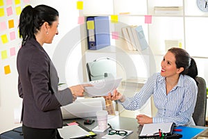 Two women chat to each other in the office.