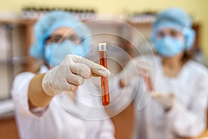 Two women in chemistry laboratory examining test tubes with red substance