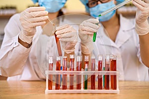 Two women in chemistry laboratory examining test tubes with red substance
