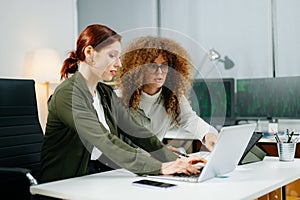 Two women coding together in a high-tech office, showcasing teamwork, software development, and female empowerment
