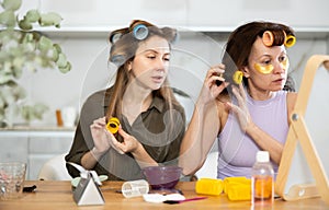 Two women curling their hair with curlers