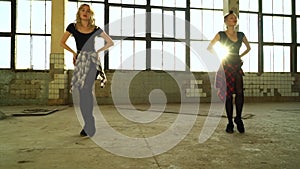 Two women dancers rehearsing in old factory hall with lens flare