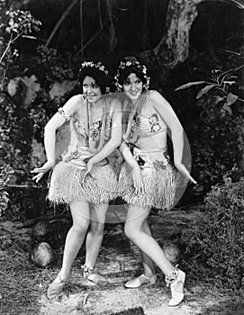 Two women dancing in grass skirts photo