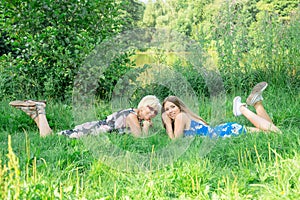 Two women of different generations lie on the grass. Mother and daughter. Grandmother and granddaughter Grandmother and granddau