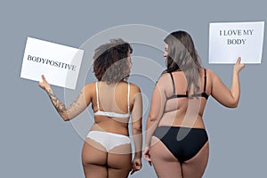 Two women of different physique in underwear standing with their backs. photo