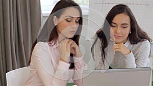 Two women discuss something on laptop at the office