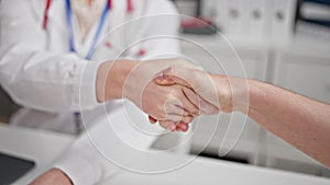 Two women doctor and patient having consultation shake hands at clinic