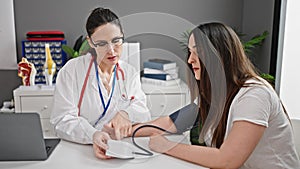 Two women doctor and patient measuring pulse using tensiometer at clinic